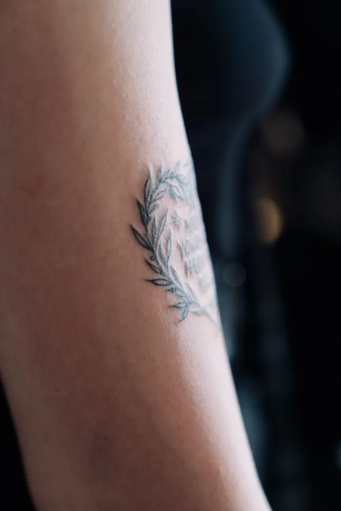 Tatouage au trait fin représentant une feuille, sur un avant-bras