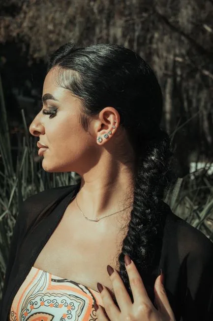 Profil d'une femme, plusieurs bijoux alignés sur l'oreille.