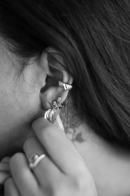 Oreille en noir et blanc, plusieurs anneaux posés sur le cartilage.