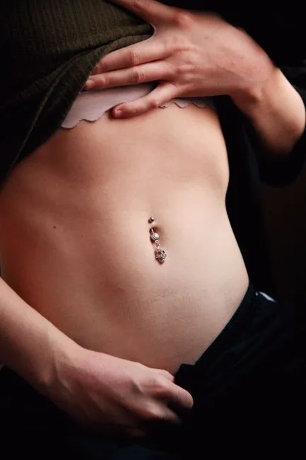 Ventre en gros plan, bijou posé au nombril.