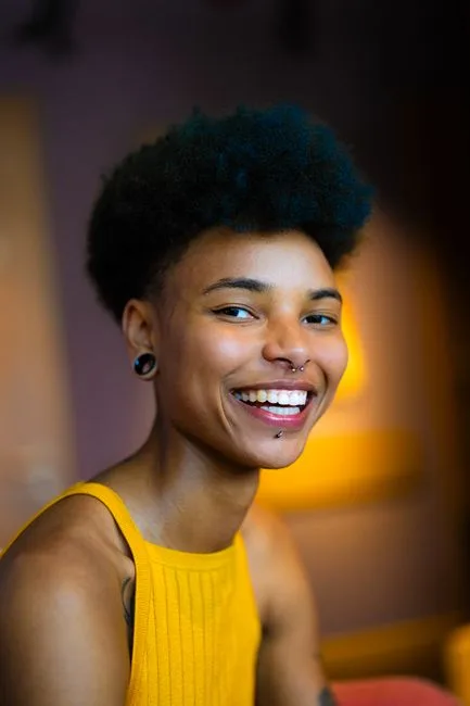 Portrait souriant, septum et plug au lobe.
