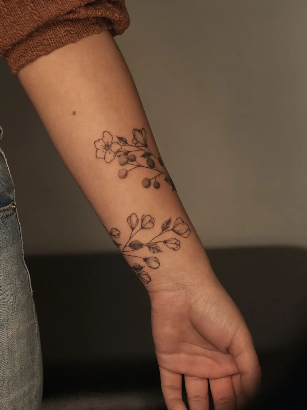 Tatouage floral au trait noir sur un avant-bras