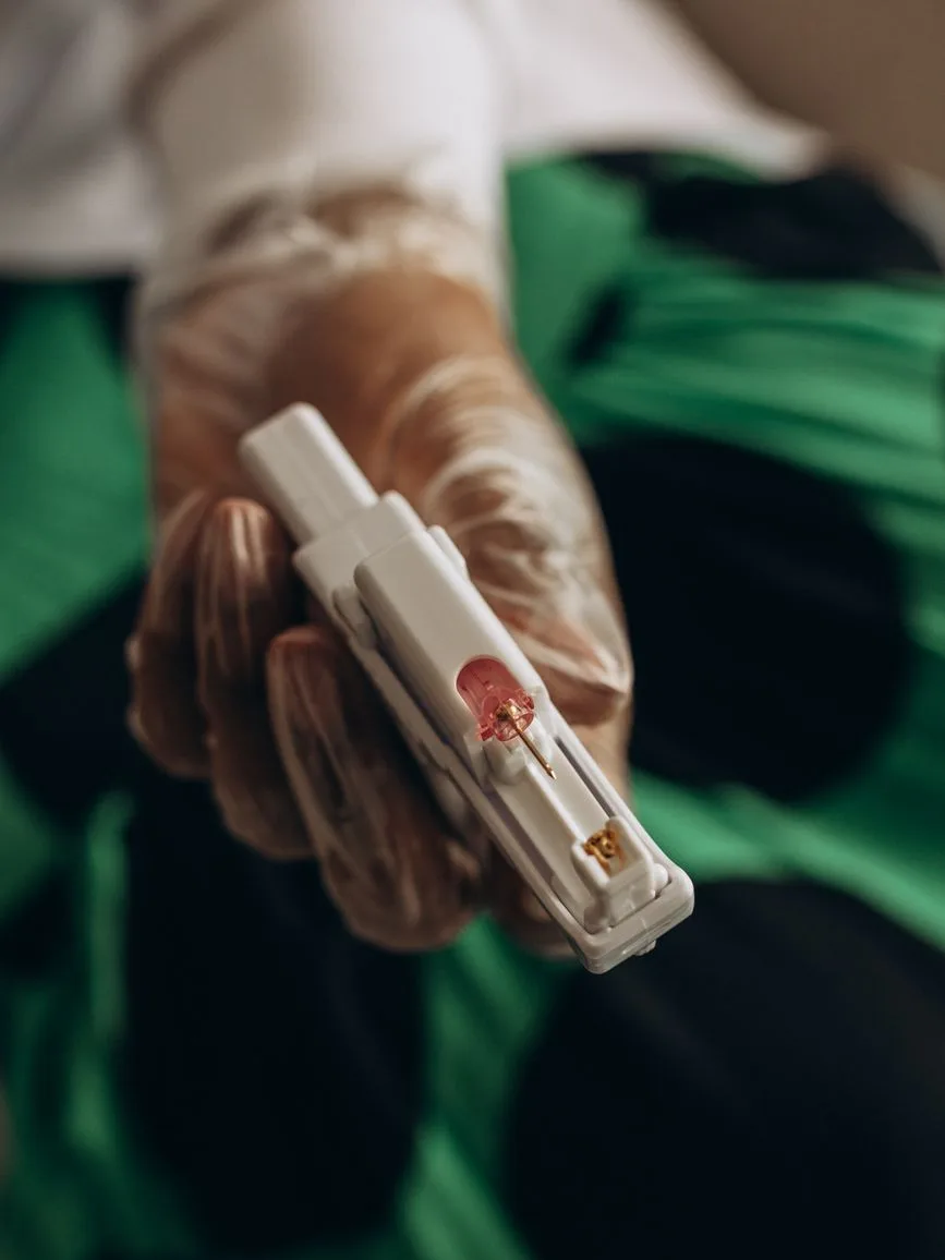 Main gantée tenant un pistolet à percer les oreilles