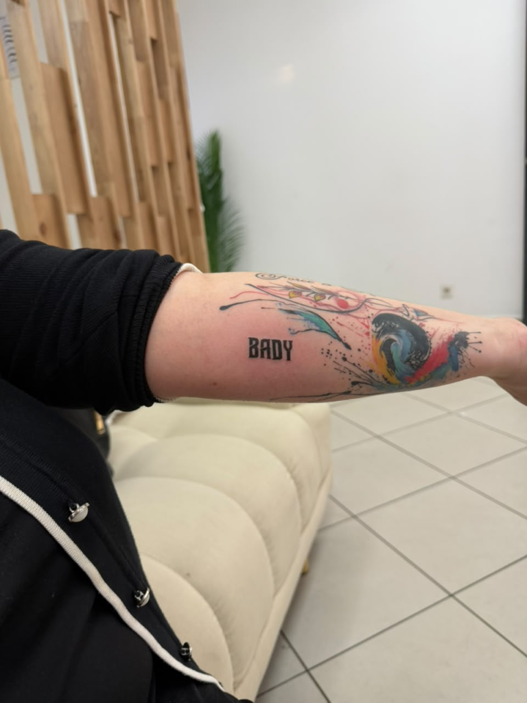 Lettrage et motif coloré — tatouage réalisé au studio AUREA Lab, Antananarivo